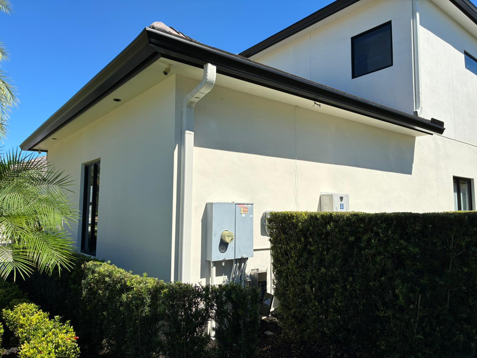 Dark seamless gutters and a white downspout visible on a residential building with a tile roof
